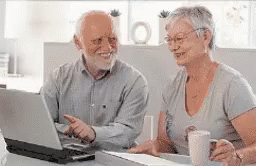 two elderly adults look at a laptop screen