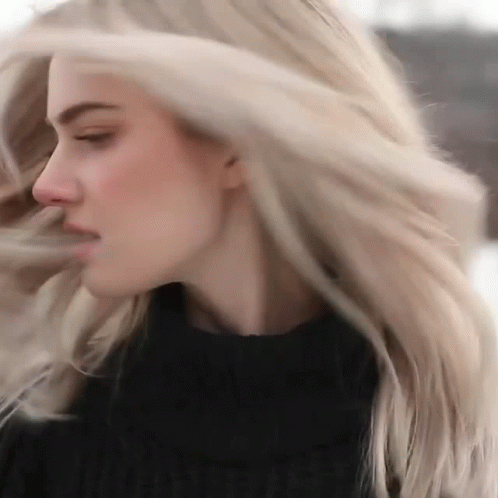a woman with white hair blowing her blonde locks
