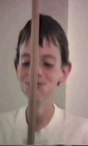 the boy smiles and looks through the blinds