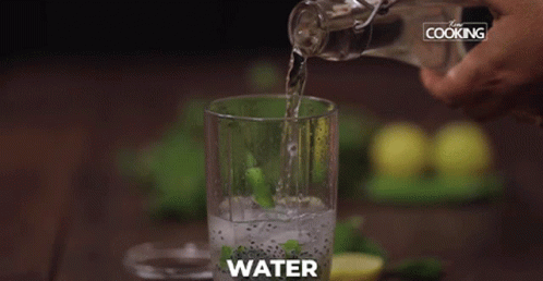 hand is pouring water in a glass full of solution