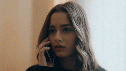 a woman talking on the phone wearing a black sweater