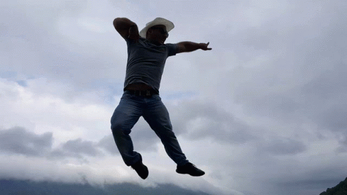 a man jumps up into the air in front of cloudy skies