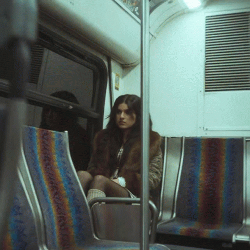 a woman is sitting on the subway looking back