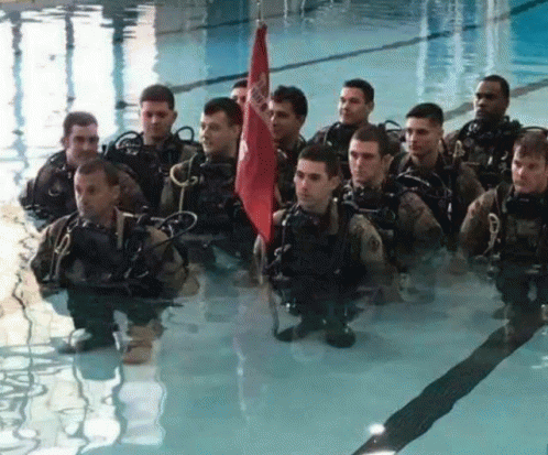 some military men are in water holding blue umbrellas
