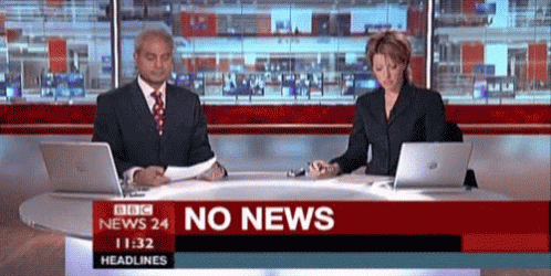 two people sitting on laptops with a news reporter