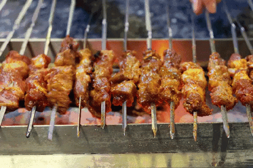 skewers of blue food sit outside on a grill
