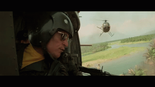 a man looking out of an helicopter window as it flies by