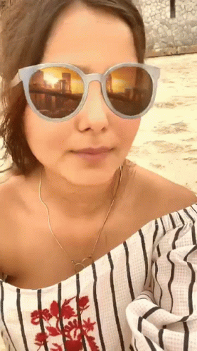 a woman wearing sunglasses looking at the camera