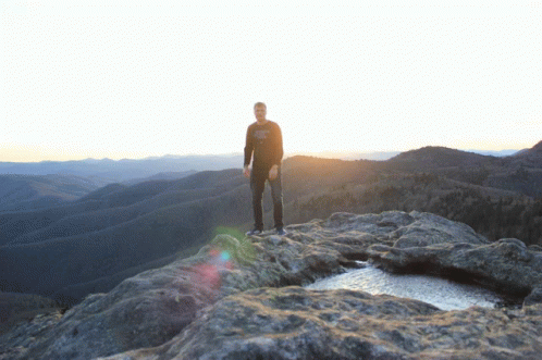 a man standing at the top of a very steep mountain