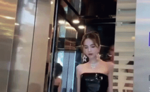 a model with white and black clothes is walking through a glass door