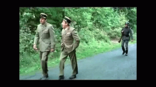 men in uniforms walking down a road on a dirt road