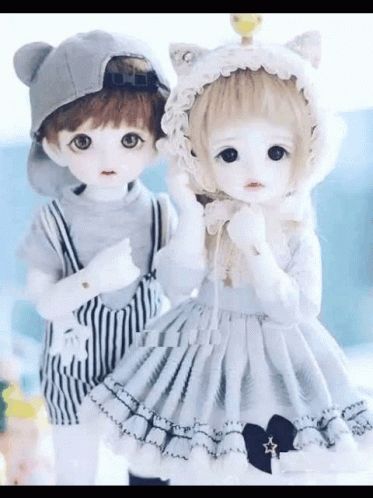two dolls in cute clothing stand next to each other