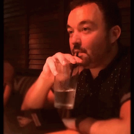 a man sitting at a table drinking some beverage
