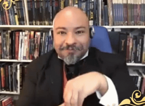 a bald man in a suit holding a pen and looking at the camera