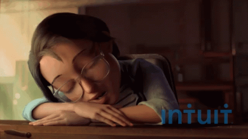 a girl with glasses looks down while resting her head on a desk