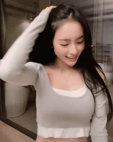 a woman in white top holding her hair behind her head