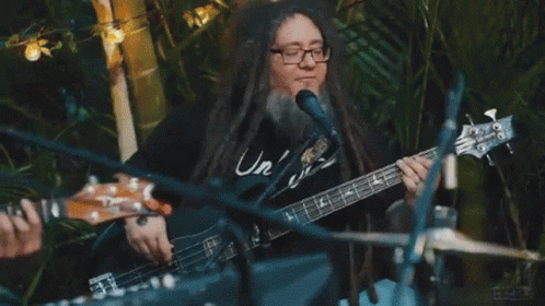 a man with long hair and glasses playing a guitar