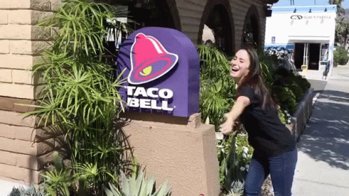 a lady is posing outside of taco bell
