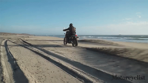 man on a motorcycle driving on the beach