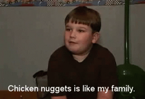 a small boy in a black shirt with the words chicken nuggets is like my family
