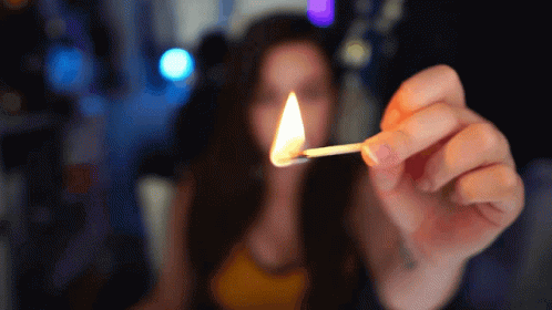 a woman holding a lit match in her left hand