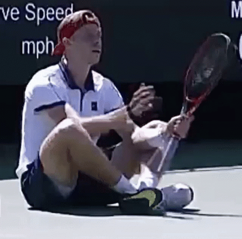 a tennis player sitting on the ground in a game of tennis
