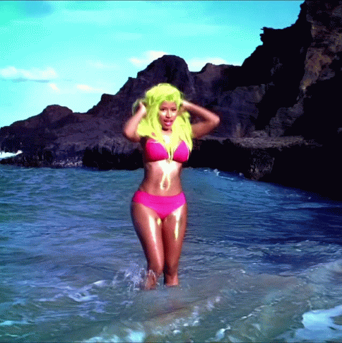 a woman with blue and pink hair stands in water near the shore