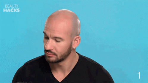 a bald headed man with a beard has his eye closed and is on the left side of his face