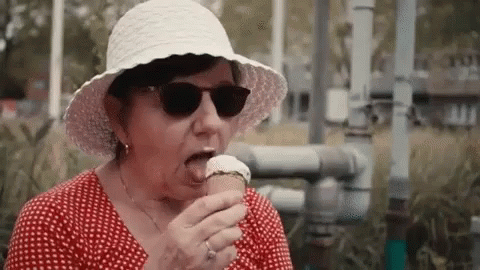 a lady with sun glasses on eating an ice cream cone