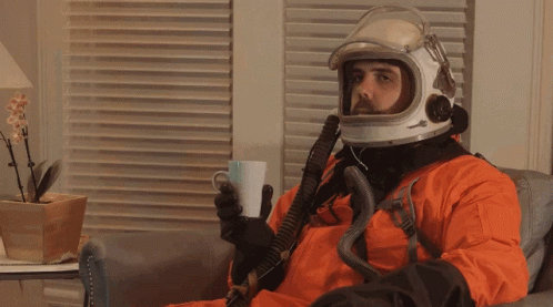 a man in a spacesuit drinking coffee while sitting on a couch
