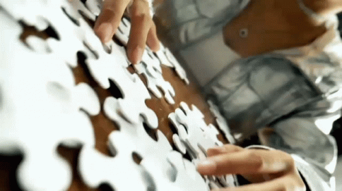 a person with gloves on a piece of puzzle