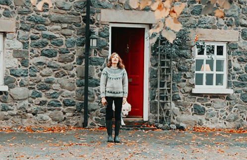 a woman wearing boots is standing outside a house