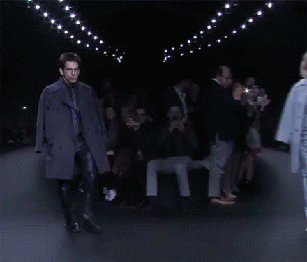 a model walks down the runway with many people watching