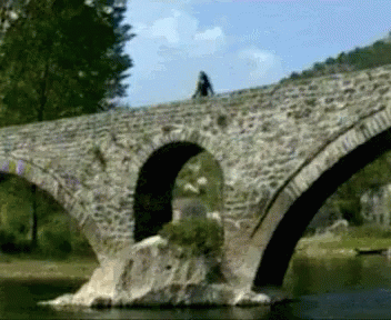 two people riding on an old stone bridge