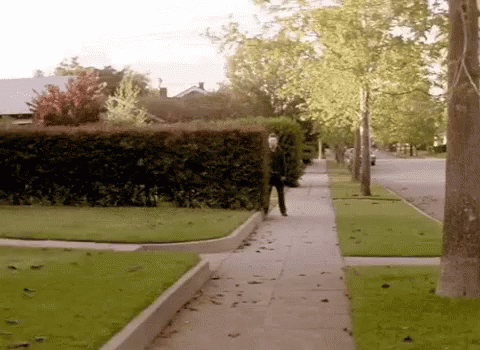 the man is walking down the sidewalk in the neighborhood