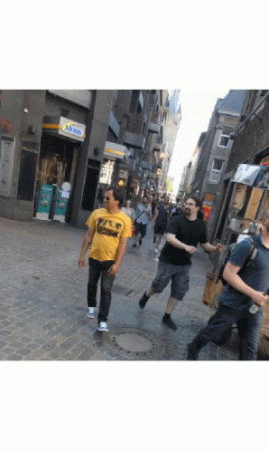some guys are walking in the streets and one is throwing a frisbee