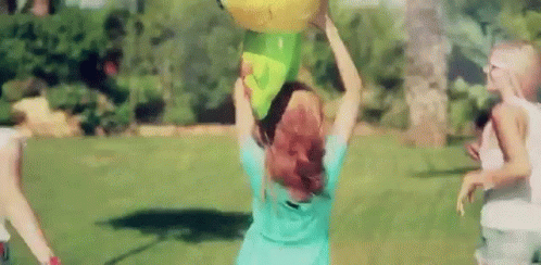 woman in yellow dress holding up a frisbee in park