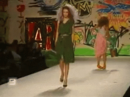 a model wearing a green outfit and walking down the runway