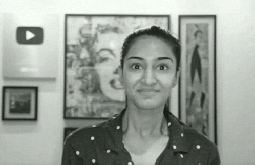 woman in black and white pograph, with artwork behind her