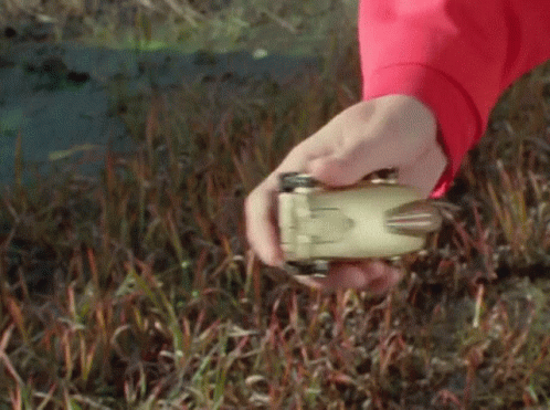 a hand that is holding a device in the grass