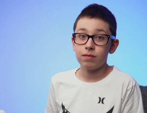 a boy with blue hair wearing glasses looks directly in the camera