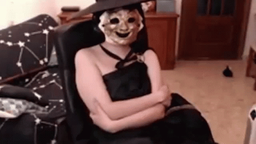 a person sitting in a chair with a halloween face mask on
