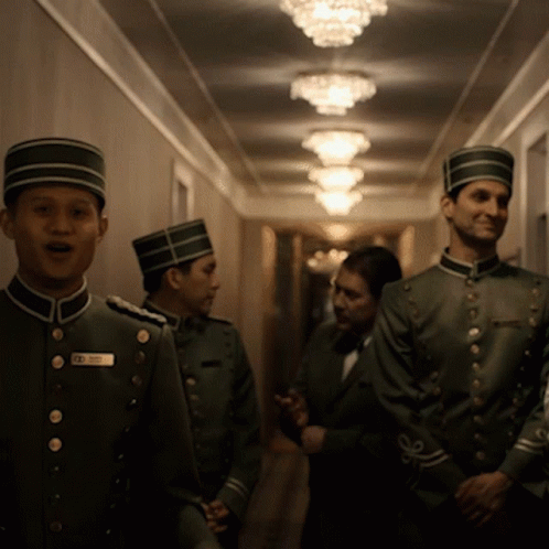 three men in military uniforms stand in a hallway