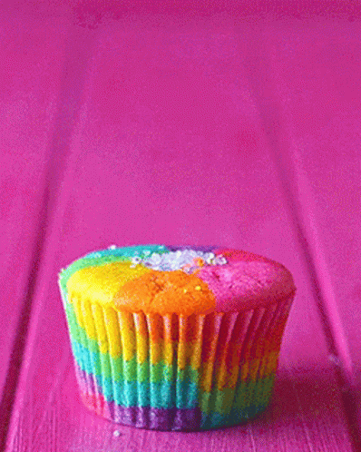 blue cupcake with rainbow icing on purple table