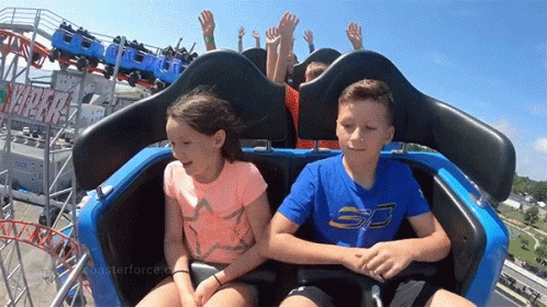 two boys sitting in the seat of a roller coaster