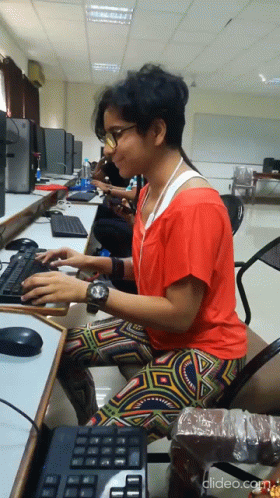 an asian man sits at his desk working on two computers