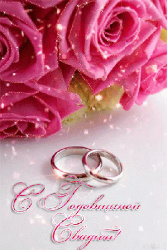 two wedding rings sitting on top of purple roses
