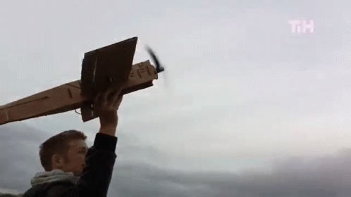 a person with a computer holding up a paper airplane in the air