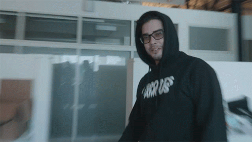 a man wearing glasses and sweatshirt in a building