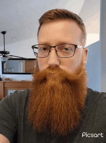 a man with glasses and a beard looks intently at the camera